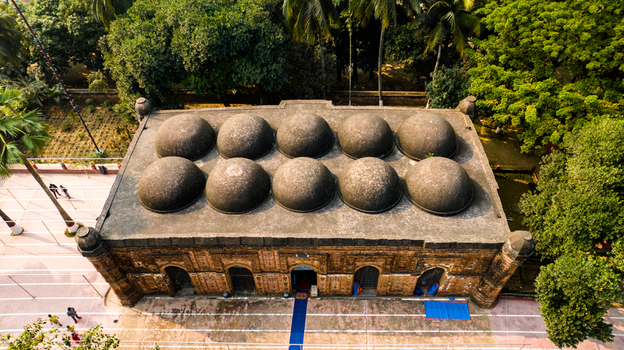 Aerial view of the historic Bagha Shahi Mosque with its ten domes and terracotta brickwork set within a courtyard surrounded by trees in Rajshahi Rajshahi Division Bangladesh.