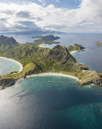 Aerial view of Padar Island featuring rugged green hills crescent shaped beaches and turquoise waters in Komodo East Nusa Tenggara Indonesia. Aerial view of Padar Island featuring rugged green hills crescent shaped beaches and turquoise waters in Komodo East Nusa Tenggara Indonesia.