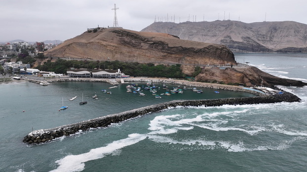 Aerial view of the Morro Solar hill with the Cristo del Pacifico statue overlooking the small fishing bay filled with boats and a stone breakwater Chorrillos Provincia de Lima Peru.