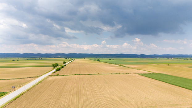 Aerial view of vast agricultural fields and a straight road under a dramatic cloudy sky in Novi Sad Vojvodina Serbia. Aerial view of vast agricultural fields and a straight road under a dramatic cloudy sky in Novi Sad Vojvodina Serbia.