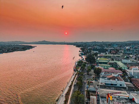 Aerial view of the Mahakam River at sunset with the city skyline urban buildings and waterfront roads in Samarinda East Kalimantan Indonesia. Aerial view of the Mahakam River at sunset with the city skyline urban buildings and waterfront roads in Samarinda East Kalimantan Indonesia.