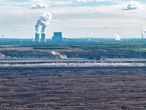 Aerial view of Tagebau Welzow Sud brown coal open pit mine with industrial power plant cooling towers emitting steam under a blue sky in Spremberg Brandenburg Germany. Aerial view of Tagebau Welzow Sud brown coal open pit mine with industrial power plant cooling towers emitting steam under a blue sky in Spremberg Brandenburg Germany.