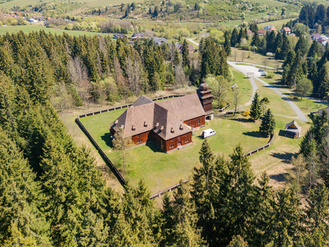 Aerial view of the Wooden Articular Church of Svaty Kriz surrounded by dense evergreen forests and rolling green hills in Svaty Kriz Zilinsky kraj Slovakia.