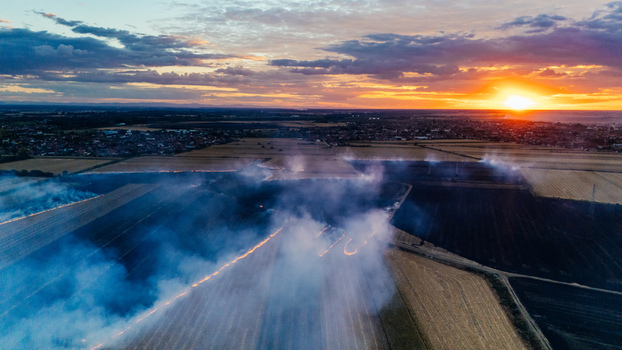 Aerial view of a field on fire at sunset with thick smoke rising over agricultural land in Sremska Mitrovica Vojvodina Serbia. Aerial view of a field on fire at sunset with thick smoke rising over agricultural land in Sremska Mitrovica Vojvodina Serbia.