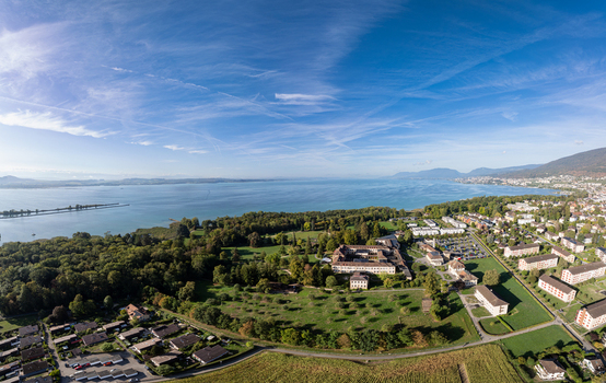 Aerial view of Marin Centre and surrounding residential area lush green parkland and the expansive Lake Neuchatel under a clear blue sky in Latena Neuchatel Switzerland. Aerial view of Marin Centre and surrounding residential area lush green parkland and the expansive Lake Neuchatel under a clear blue sky in Latena Neuchatel Switzerland.