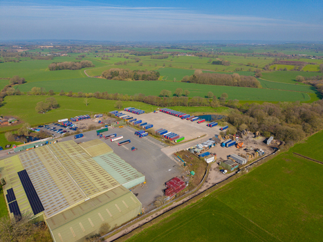 Aerial view of Ladfordfields Industrial Estate with rows of parked semi truck trailers large warehouse buildings and surrounding green fields in Stafford England United Kingdom. Aerial view of Ladfordfields Industrial Estate with rows of parked semi truck trailers large warehouse buildings and surrounding green fields in Stafford England United Kingdom.