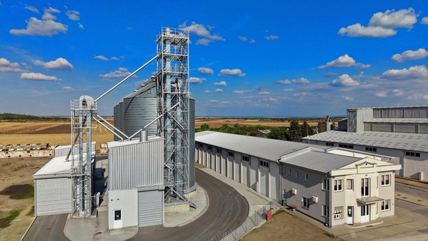Aerial view of storage silo Bavaniste with metal grain bins industrial buildings and surrounding agricultural fields under a blue sky Bavaniste Vojvodina Serbia.