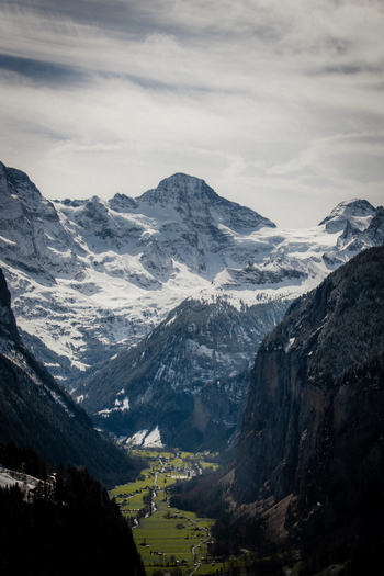 View of snow dusted peaks pierce the sky above a verdant valley a tapestry of textures and tones painting a serene mountain landscape Lauterbrunnen Switzerland. View of snow dusted peaks pierce the sky above a verdant valley a tapestry of textures and tones painting a serene mountain landscape Lauterbrunnen Switzerland.