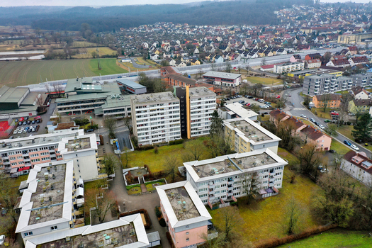 Aerial view of residential apartment blocks and urban infrastructure with green spaces and a highway in the background in Forchheim Bavaria Germany.