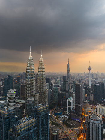 Kuala Lumpur Malaysia 11 March 2026 Aerial view of the Petronas Twin Towers and the city skyline under a dramatic sunset sky with dark storm clouds.