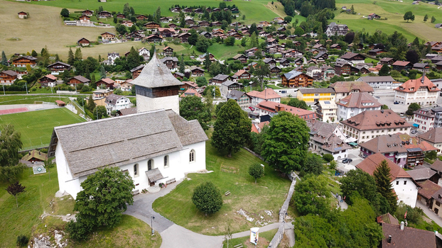 Aerial view of the Temple of Chateau d Oex and traditional alpine chalets nestled in a lush green valley under soft daylight Chateau d Oex Vaud Switzerland. Aerial view of the Temple of Chateau d Oex and traditional alpine chalets nestled in a lush green valley under soft daylight Chateau d Oex Vaud Switzerland.