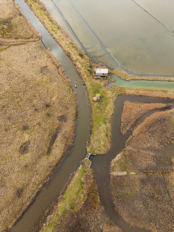 Aerial view of Lake Atanasovsko with narrow canals a small abandoned building and dry grassy wetlands in Burgas Burgas Bulgaria. Aerial view of Lake Atanasovsko with narrow canals a small abandoned building and dry grassy wetlands in Burgas Burgas Bulgaria.