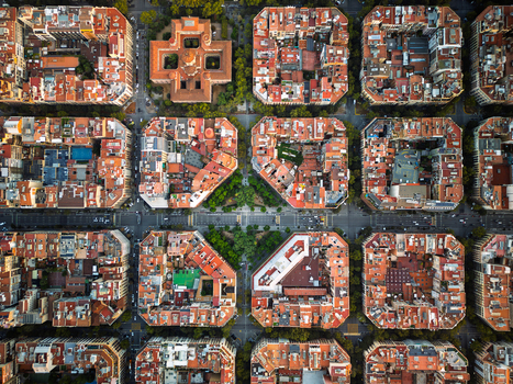 Aerial view of the iconic octagonal city blocks and grid layout of the Eixample district with red rooftops and inner courtyards in Barcelona Catalonia Spain.