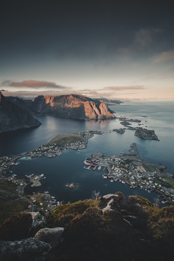 View of the dramatic Reinebringen mountain peak overlooking the coastal village of Moskenes with deep blue waters scattered islands and rugged mountains in Moskenes Nordland Norway.
