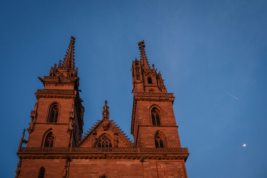 Basel Switzerland 10 March 2025 View of the majestic Basel Minster its spires piercing the twilight sky bathed in the warm glow of the setting sun. Basel Switzerland 10 March 2025 View of the majestic Basel Minster its spires piercing the twilight sky bathed in the warm glow of the setting sun.