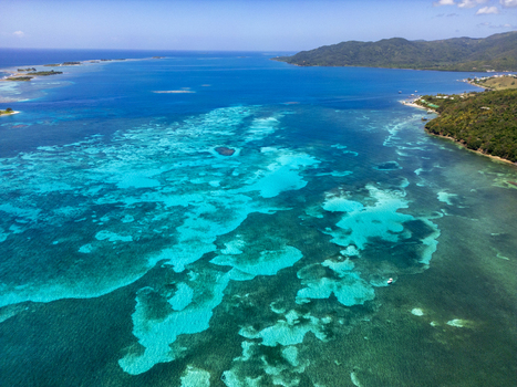 Aerial view of Guanaja island featuring vibrant turquoise coral reefs lush green hills and the deep blue Caribbean Sea Guanaja Bay Islands Department Honduras. Aerial view of Guanaja island featuring vibrant turquoise coral reefs lush green hills and the deep blue Caribbean Sea Guanaja Bay Islands Department Honduras.