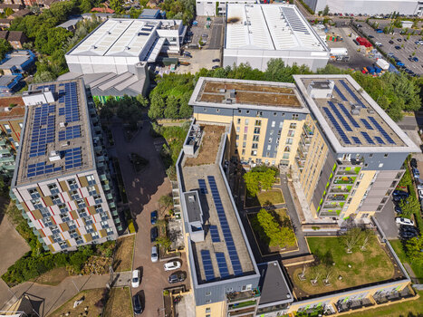 Aerial view of modern apartment buildings with solar panels on the roofs green courtyards and surrounding urban infrastructure in London England United Kingdom. Aerial view of modern apartment buildings with solar panels on the roofs green courtyards and surrounding urban infrastructure in London England United Kingdom.
