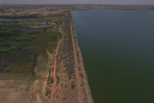 Aerial view of Minjibir Dam with its long embankment separating the reservoir from the surrounding arid landscape and agricultural fields in Kano Kano State Nigeria. Aerial view of Minjibir Dam with its long embankment separating the reservoir from the surrounding arid landscape and agricultural fields in Kano Kano State Nigeria.