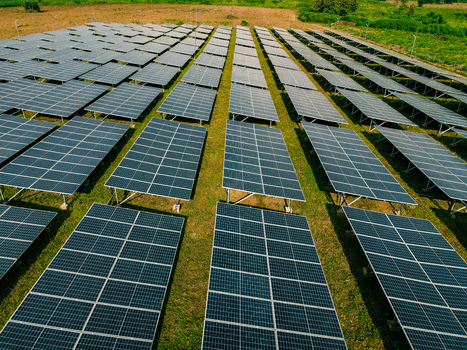 Aerial view of rows of photovoltaic solar panels installed in a field under bright sunlight in Ogun State Nigeria.