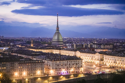 Aerial view of the Mole Antonelliana and the illuminated city skyline with the Alps in the background at twilight in Turin Piedmont Italy. Aerial view of the Mole Antonelliana and the illuminated city skyline with the Alps in the background at twilight in Turin Piedmont Italy.