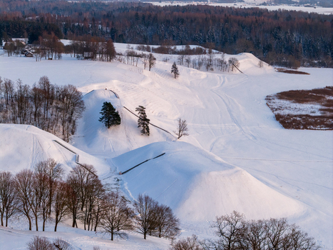 Aerial view of the snow covered hillforts of Kernave Archaeological Site surrounded by winter forests and fields under soft light in Kernave Vilnius County Lithuania.