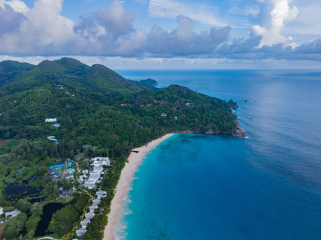 Aerial view of turquoise waters meeting the white sandy beach framed by lush green hills speckled with buildings Quatre Bornes Seychelles. Aerial view of turquoise waters meeting the white sandy beach framed by lush green hills speckled with buildings Quatre Bornes Seychelles.