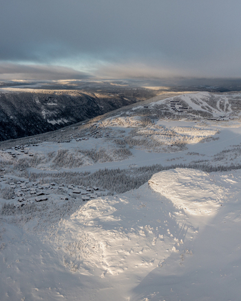 Aerial view of Gaustablikk Fjellresort nestled in the snow covered mountains with scattered cabins and dramatic winter light in Rjukan Telemark Norway. Aerial view of Gaustablikk Fjellresort nestled in the snow covered mountains with scattered cabins and dramatic winter light in Rjukan Telemark Norway.