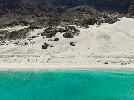 Aerial view of where the stark rugged mountains meet the pristine white sands and turquoise waters Erissel Socotra Yemen.
