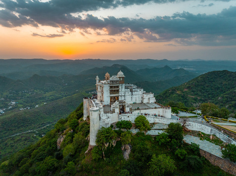 Aerial view of Sajjangarh Palace also known as the Monsoon Palace perched on a hilltop overlooking the Aravalli hills at sunset in Udaipur Rajasthan India.