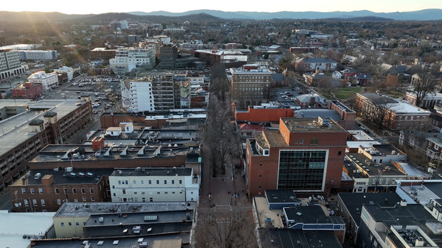 Aerial view of the city of Charlottesville at sunset featuring urban buildings rooftops and streets in Charlottesville Virginia United States.