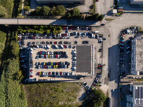 Aerial view of a busy parking lot filled with numerous cars parked in orderly rows featuring a large solar panel array covering a section of the lot situated in Ancona Marche Italy. Aerial view of a busy parking lot filled with numerous cars parked in orderly rows featuring a large solar panel array covering a section of the lot situated in Ancona Marche Italy.