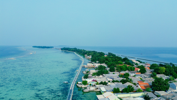 Aerial view of Tidung Island featuring a long bridge connecting land surrounded by turquoise waters lush trees and houses in South Kepulauan Seribu Jakarta Indonesia. Aerial view of Tidung Island featuring a long bridge connecting land surrounded by turquoise waters lush trees and houses in South Kepulauan Seribu Jakarta Indonesia.