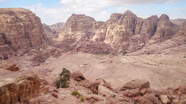 View of the rugged desert landscape and sandstone rock formations near Petra featuring arid terrain rocky cliffs and sparse vegetation in Wadi Musa Ma an Governorate Jordan. View of the rugged desert landscape and sandstone rock formations near Petra featuring arid terrain rocky cliffs and sparse vegetation in Wadi Musa Ma an Governorate Jordan.