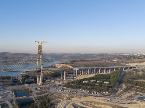 Aerial view of the construction of a large cable stayed bridge with a tall pylon cranes and concrete pillars extending over a river in Istanbul Istanbul Turkiye.