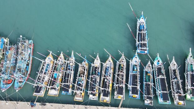 Aerial view of colorful fishing boats moored in orderly rows along the concrete pier in the harbor of Bakauheni Lampung Indonesia.