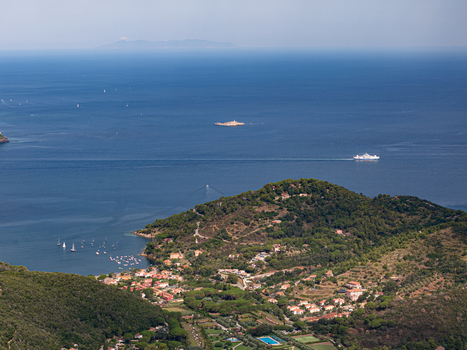 Aerial view of the historic Castello del Volterraio overlooking the coastal landscape lush green hills and the blue waters of the bay with boats in Portoferraio Toscana Italy.