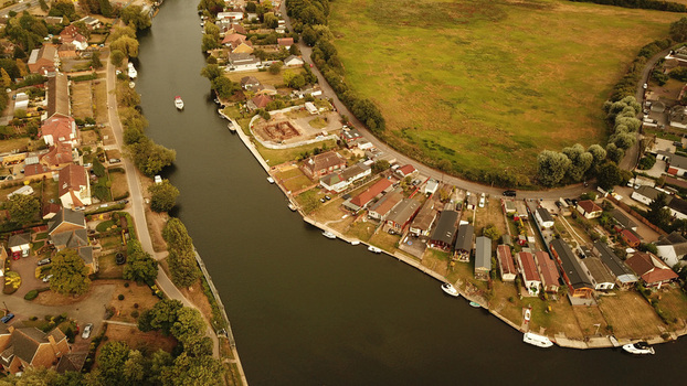 Aerial view of the Thames River flowing past residential houses and green fields in Thames United Kingdom. Aerial view of the Thames River flowing past residential houses and green fields in Thames United Kingdom.