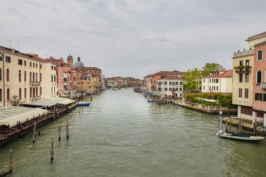 Venice Italy 06 May 2022 View of the Grand Canal lined with historic buildings wooden mooring poles and boats under a cloudy sky in Venice Veneto Italy. Venice Italy 06 May 2022 View of the Grand Canal lined with historic buildings wooden mooring poles and boats under a cloudy sky in Venice Veneto Italy.
