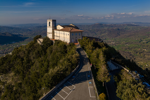 Aerial view of Santuario del Santissimo Salvatore perched on a lush green hilltop with a winding access road and panoramic views of the valley in Montella Campania Italy. Aerial view of Santuario del Santissimo Salvatore perched on a lush green hilltop with a winding access road and panoramic views of the valley in Montella Campania Italy.