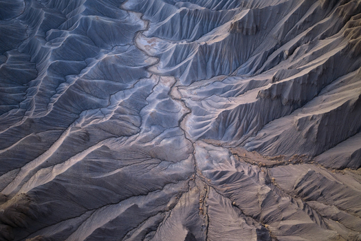 Aerial view of the intricate badlands landscape featuring deep erosion channels and grey ridges under soft light in Hanksville Utah United States.