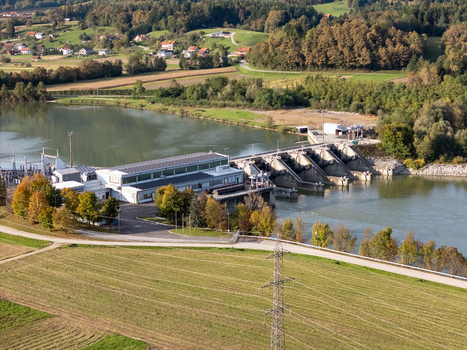 Aerial view of a hydroelectric power plant and dam on a river with an electricity pylon in the foreground and autumn trees on the surrounding hills in Slovenia. Aerial view of a hydroelectric power plant and dam on a river with an electricity pylon in the foreground and autumn trees on the surrounding hills in Slovenia.