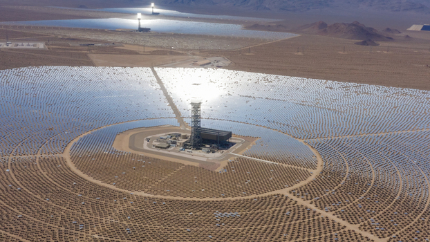 Aerial view of a large concentrated solar power plant with thousands of mirrors and central solar towers in a desert landscape United States.
