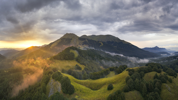 Aerial view of the Apennine mountain peaks surrounded by mist and lush green forests during a golden sunset Cerreto Laghi Emilia Romagna Italy. Aerial view of the Apennine mountain peaks surrounded by mist and lush green forests during a golden sunset Cerreto Laghi Emilia Romagna Italy.
