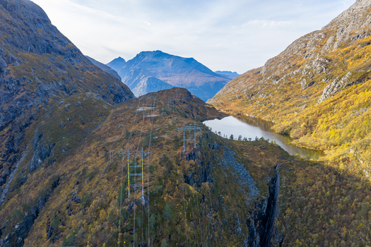 Aerial view of power lines crossing a rugged mountain landscape with a small lake and autumn foliage in Andalsnes More og Romsdal Norway. Aerial view of power lines crossing a rugged mountain landscape with a small lake and autumn foliage in Andalsnes More og Romsdal Norway.