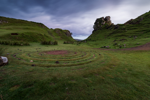 View of the stone spiral at Fairy Glen surrounded by lush green hills and a rocky outcrop under a dramatic cloudy sky in Wigan England United Kingdom. View of the stone spiral at Fairy Glen surrounded by lush green hills and a rocky outcrop under a dramatic cloudy sky in Wigan England United Kingdom.