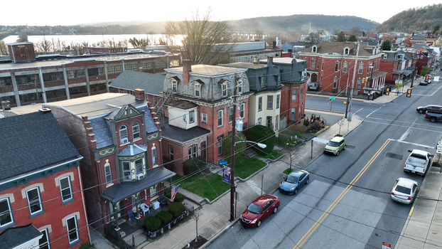 Aerial view of historic brick houses along a street with cars parked on the road and the Susquehanna River in the background at sunset in Columbia Pennsylvania United States. Aerial view of historic brick houses along a street with cars parked on the road and the Susquehanna River in the background at sunset in Columbia Pennsylvania United States.