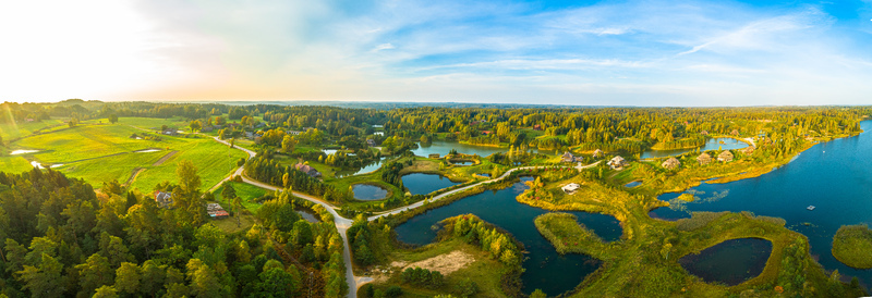 Aerial view of a lush rural landscape featuring interconnected lakes dense forests and green meadows bathed in the warm light of the golden hour Latvia. Aerial view of a lush rural landscape featuring interconnected lakes dense forests and green meadows bathed in the warm light of the golden hour Latvia.