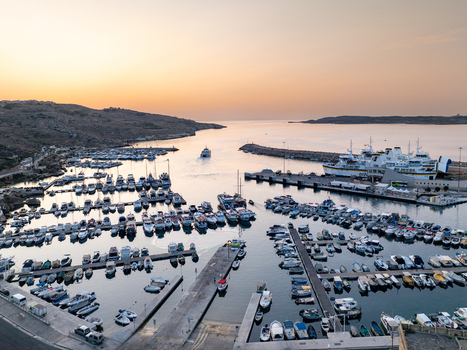 Aerial view of the Mgarr Harbour where the boats rest on the calm waters framed by the rugged coastline Mgarr Harbour Gozo Malta. Aerial view of the Mgarr Harbour where the boats rest on the calm waters framed by the rugged coastline Mgarr Harbour Gozo Malta.