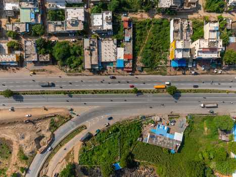 Aerial view of a multi lane highway intersection surrounded by urban buildings rooftops and green vegetation in Udaipur Rajasthan India. Aerial view of a multi lane highway intersection surrounded by urban buildings rooftops and green vegetation in Udaipur Rajasthan India.
