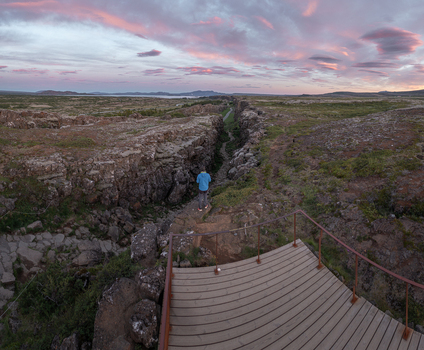 Aerial view of Thingvellir National Park with a person on a wooden deck overlooking the rocky rift valley under a sunset sky in Selfoss Blaskogabyggd Iceland. Aerial view of Thingvellir National Park with a person on a wooden deck overlooking the rocky rift valley under a sunset sky in Selfoss Blaskogabyggd Iceland.